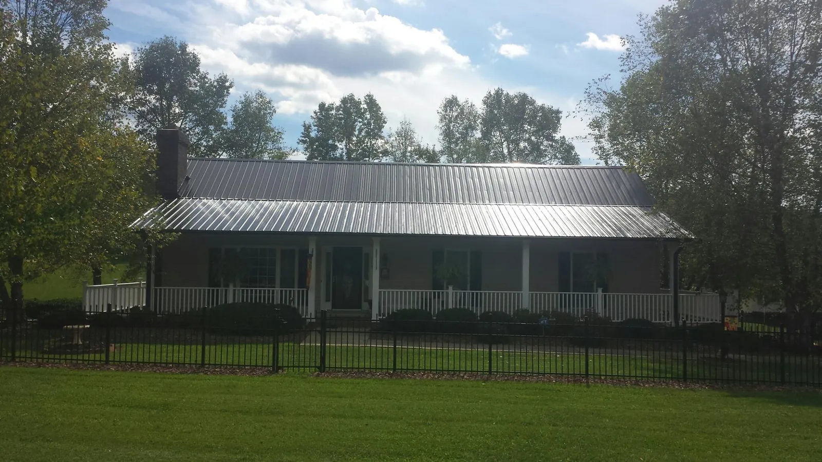 Gray metal roof on a brick ranch with a full width front porch — Gutter Guard Installation work by our crew in Etowah